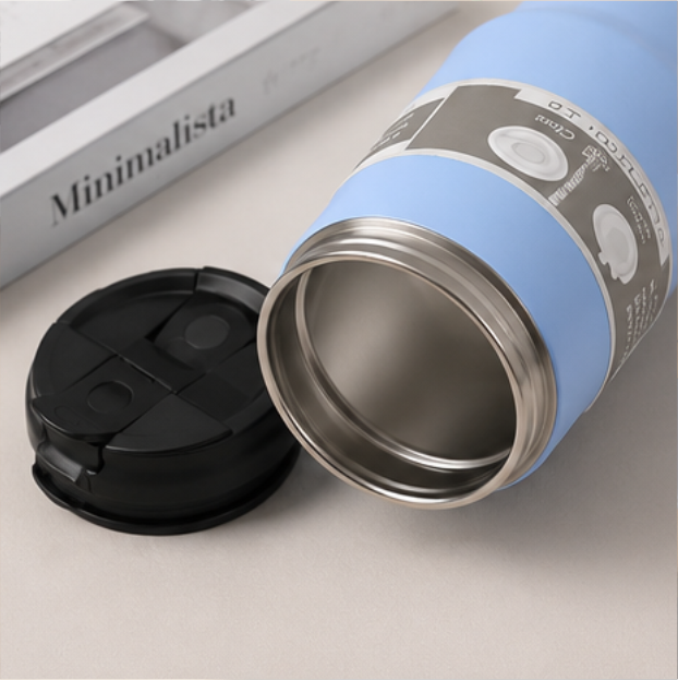 Light blue insulated tumbler with black lid removed, showing stainless steel interior, placed on a white surface